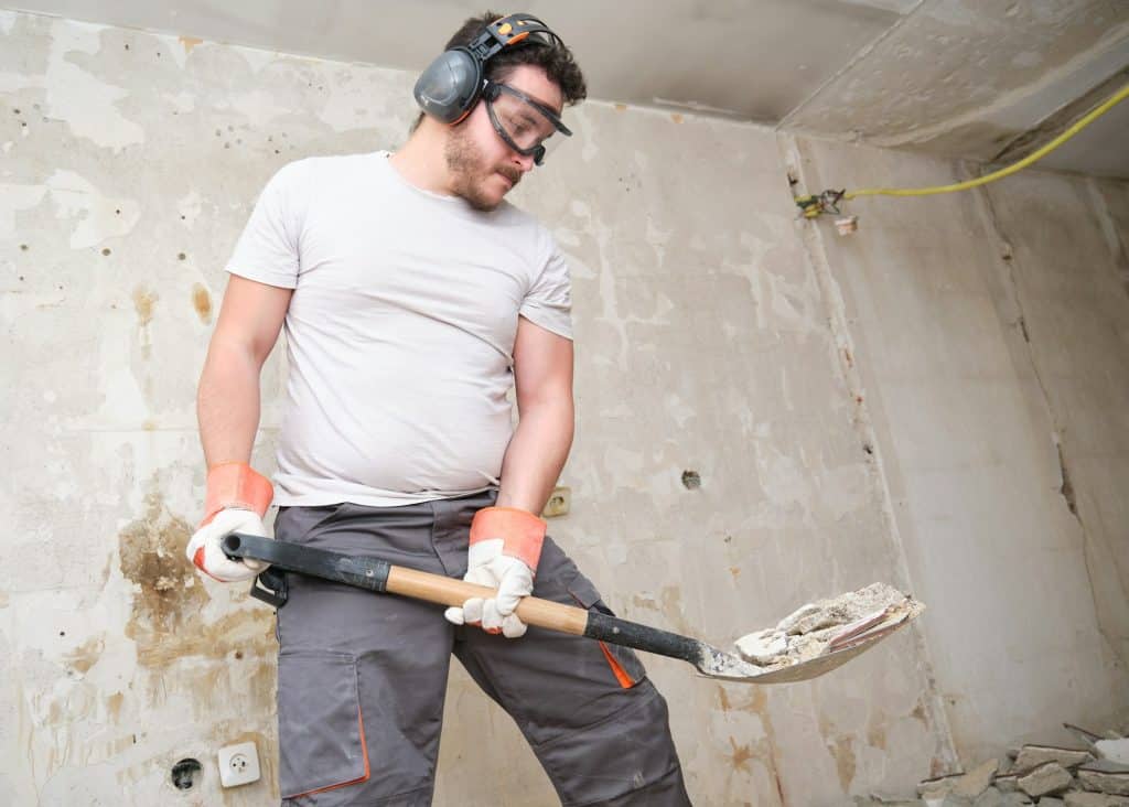 Builder collecting construction debris with a shovel. House renovation.