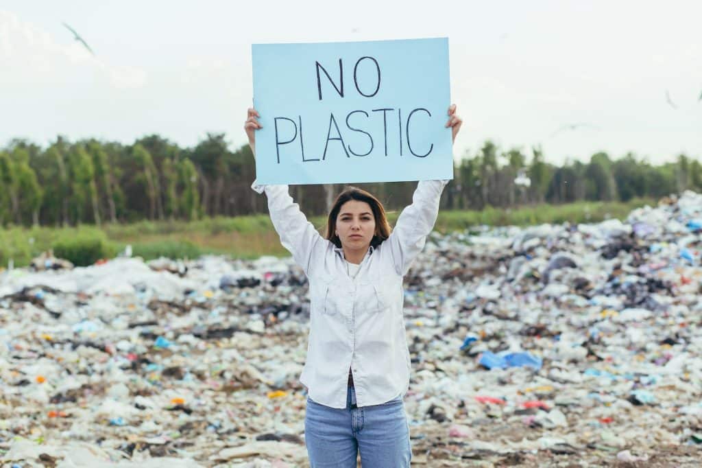 Female volunteer pickets a landfill with a poster no plastic, activist struggles with environmental