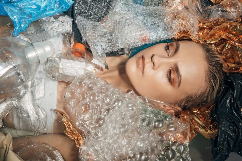 top view of young woman posing in bathtub with plastic trash, eco concept